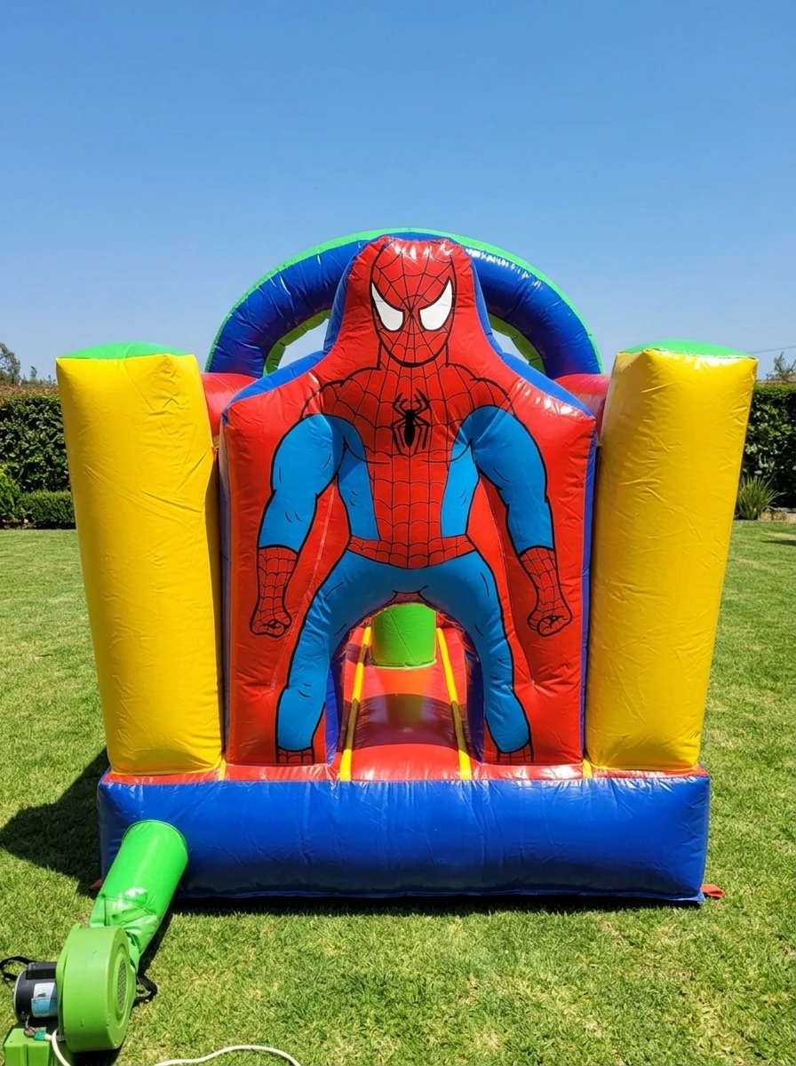 Inflable rojo y azul con la figura del Hombre Araña, columnas amarillas y soplador conectado, instalado en un jardín